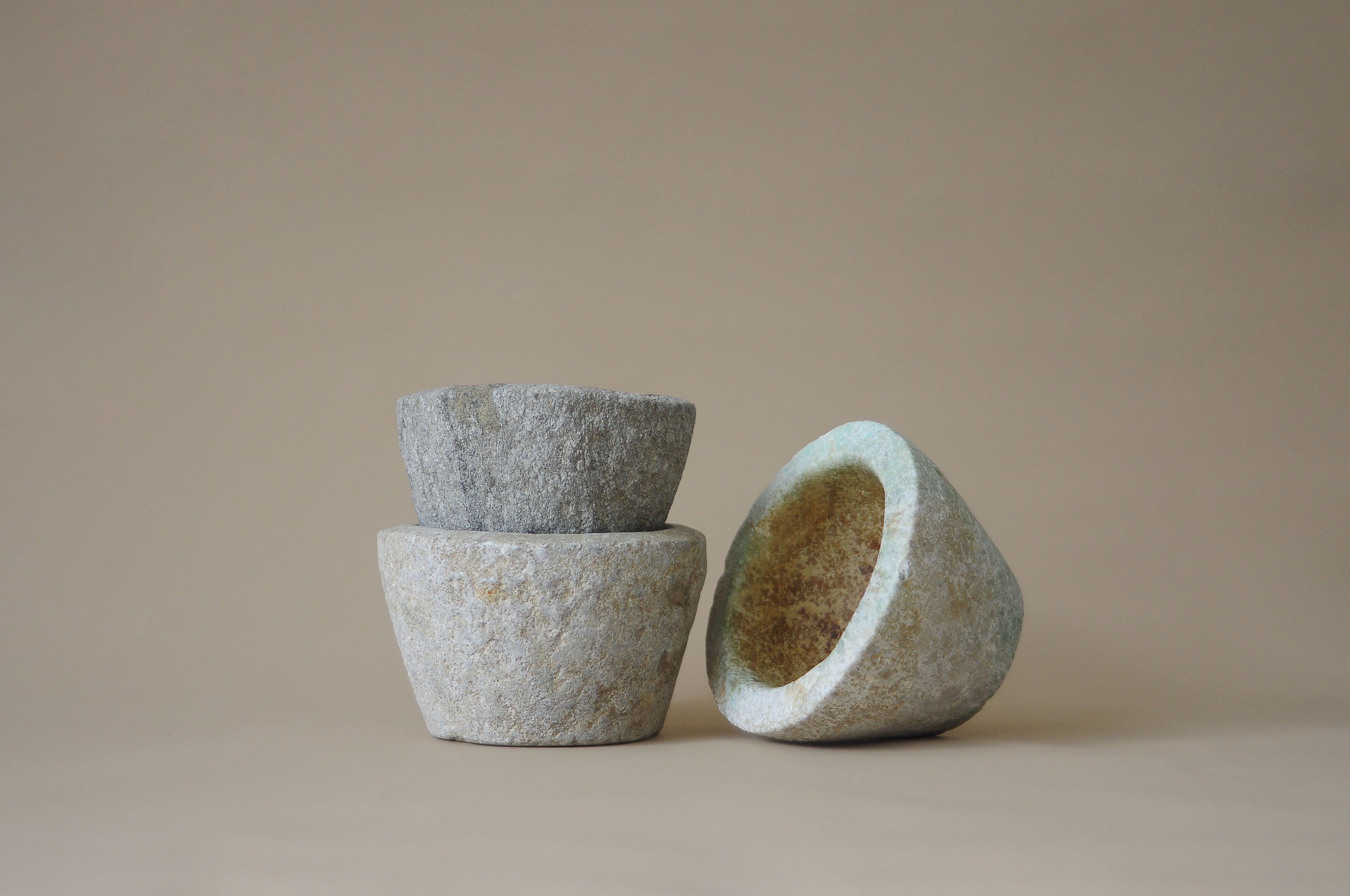 Three stone bowls of different sizes on a beige background