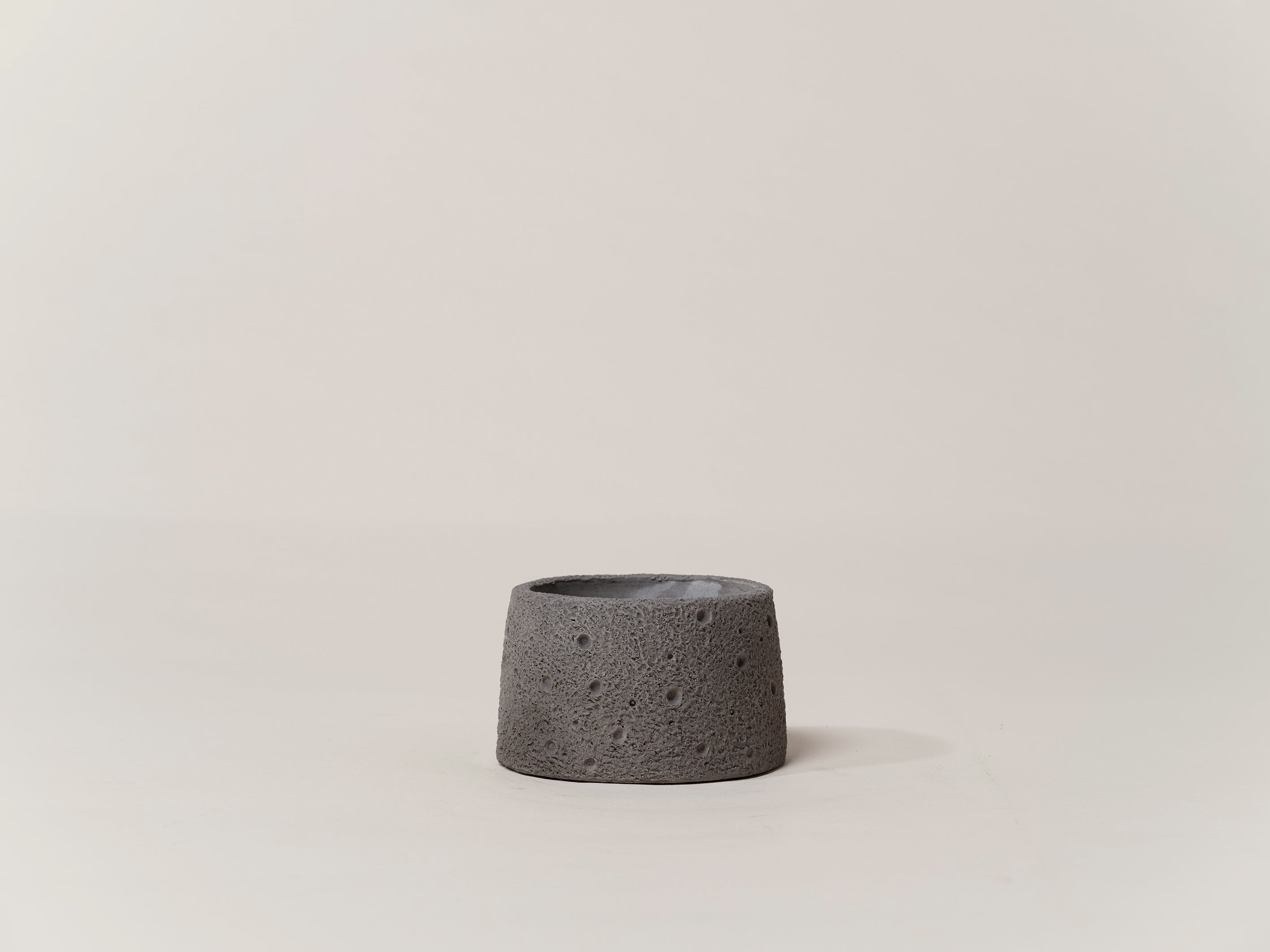 A dark grey, Nordic-style cement plant pot with a rough, rock-like texture, displayed against a neutral background.