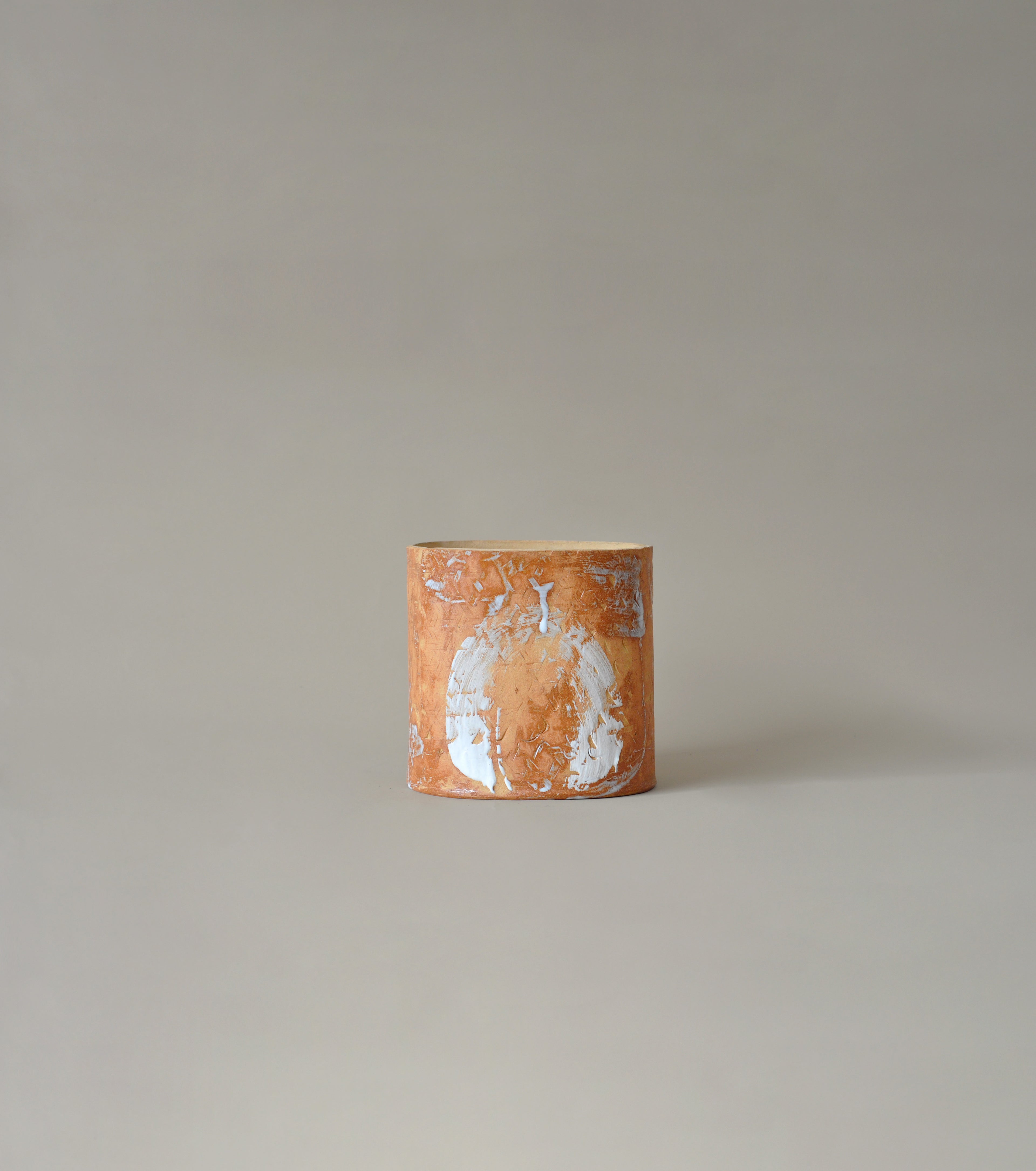 Cylindrical ceramic vase with abstract design on a plain background