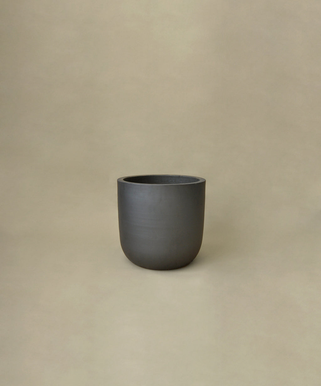 Dark gray ceramic plant pot on a beige background