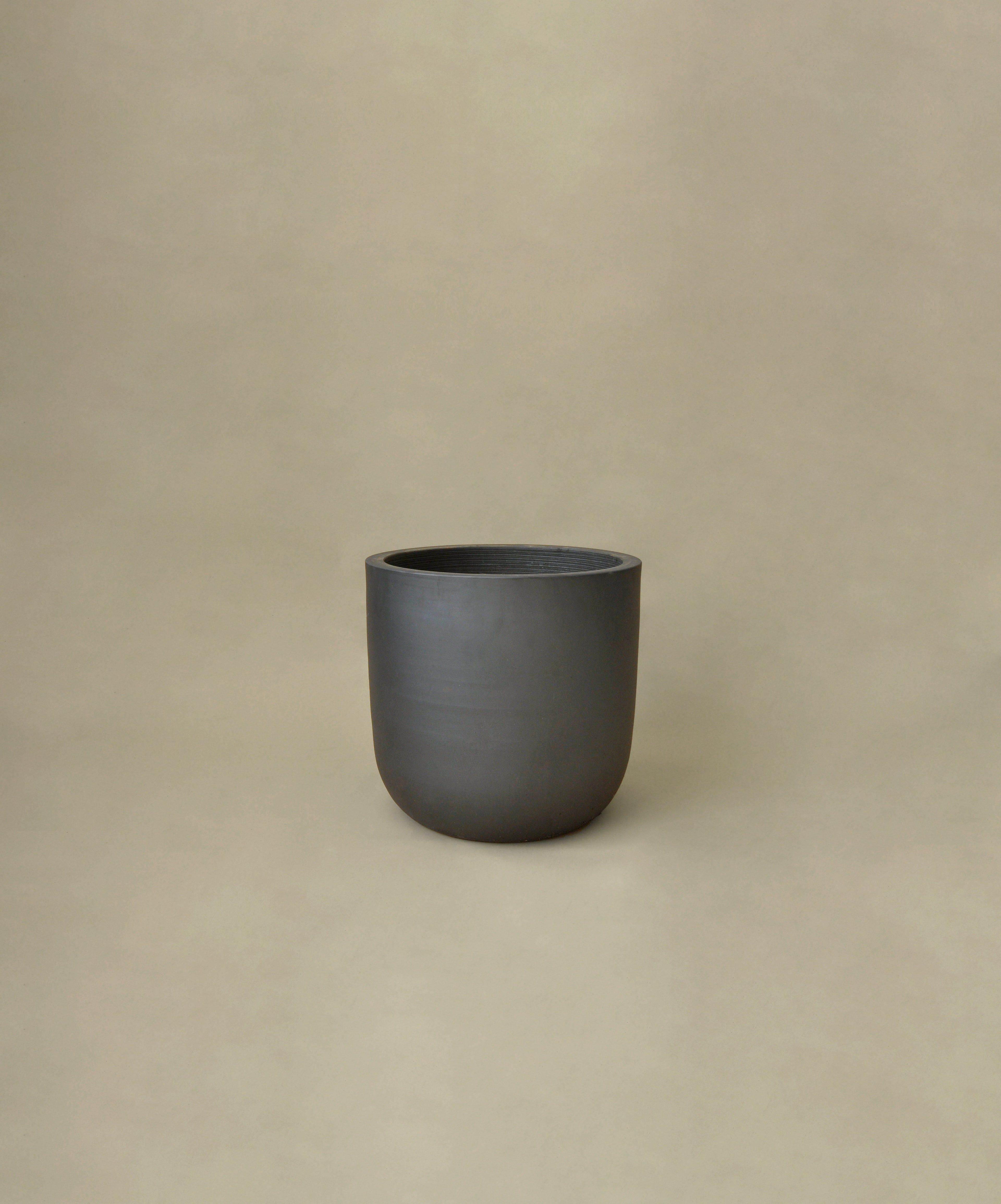 Dark gray ceramic plant pot on a beige background