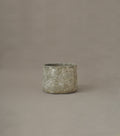 Textured ceramic pot on a brown background