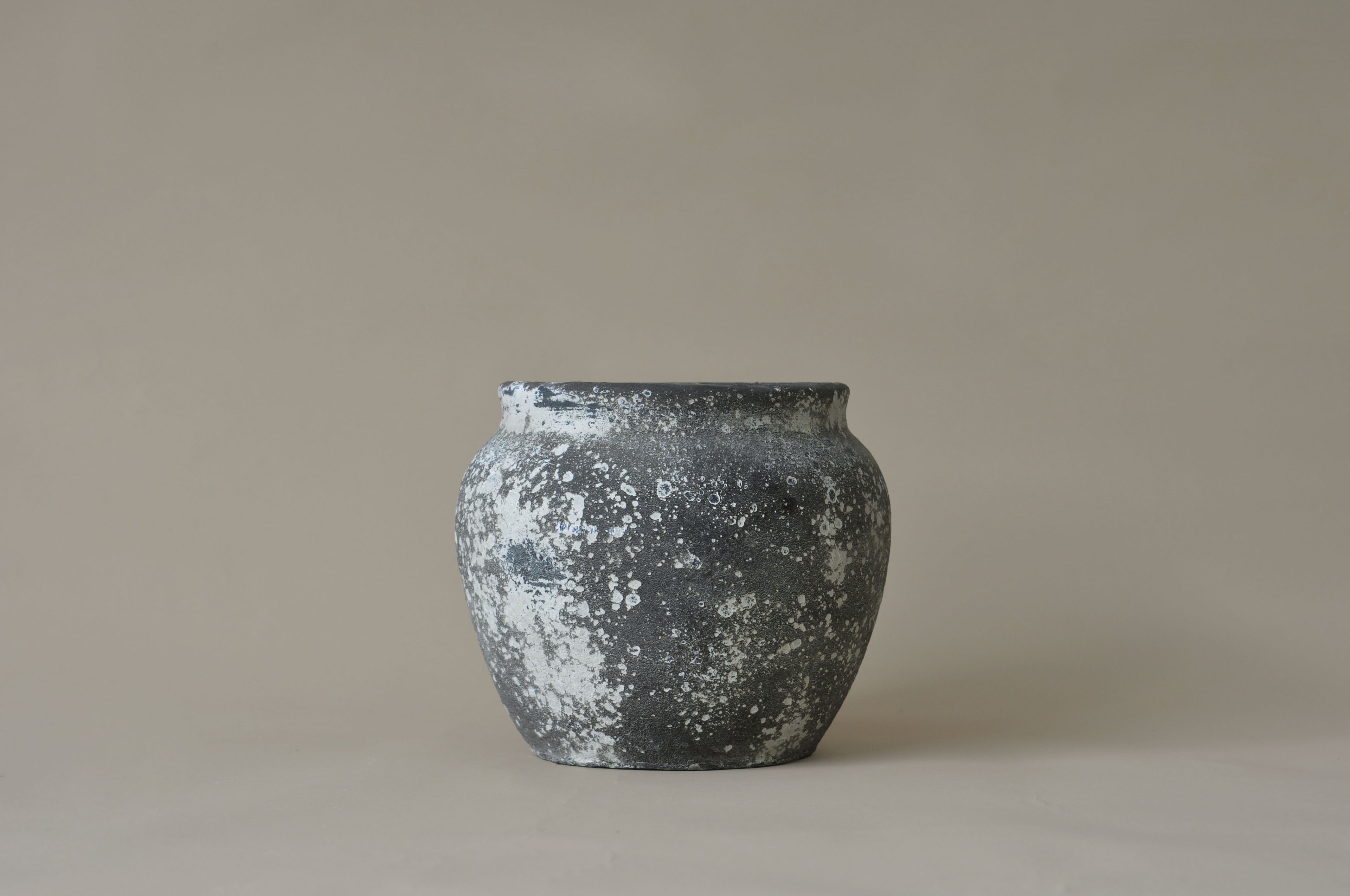 Black textured vase on a beige background